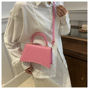 Detail of pink hourglass crossbody bag with heart embroidery and woven handle on model