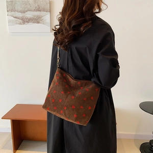 Brown corduroy tote bag with red strawberry pattern worn by a model in a retro style