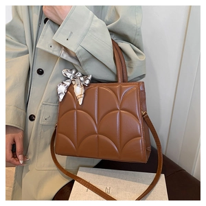 Detail of brown quilted tote bag with a silk scarf handle wrap and detachable strap