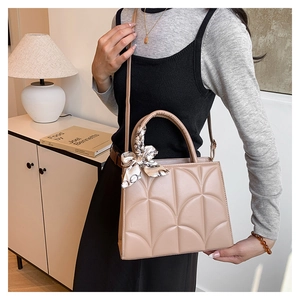 Close-up of beige quilted tote bag with silk scarf accessory and adjustable strap