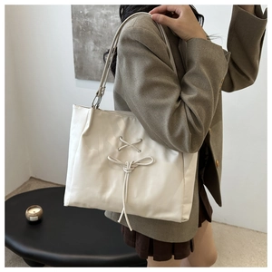Detail of white tote bag featuring decorative bow lacing and premium soft texture surface