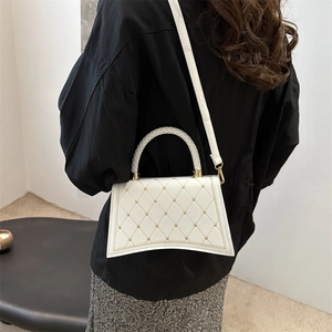 White quilted rivet handbag with heart details and curved base shown on model