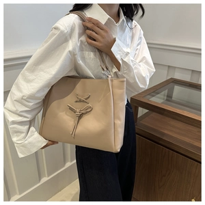Detail of beige bow tote bag with delicate cross-lacing and matte leather finish