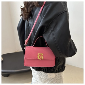 Detailed view of pink leather crossbody bag featuring gold G-buckle and pebble texture