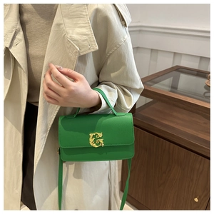 Detail of green lychee leather handbag with golden G letter hardware on beige trench coat