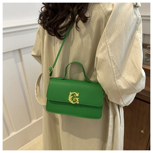 Detail of green textured leather handbag with ornate golden G buckle on a model