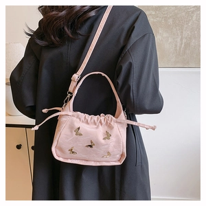 Borsa a nuvola rosa con farfalle dorate e catena indossata su abito nero
