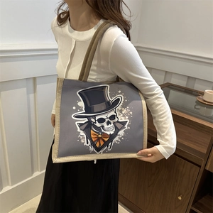 Deep grey canvas tote bag with skull illustration and beige woven trim shown by a model