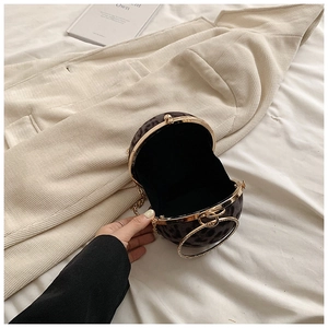 Detail view of round leopard print evening bag with rhinestone ring handle and gold chain
