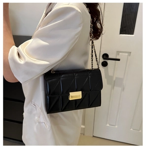 Gros plan du sac bandoulière en cuir noir matelassé avec fermoir doré et chaîne