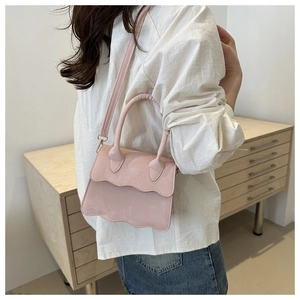 Pink crossbody bag with wavy edges and soft faux suede texture in daily life scene