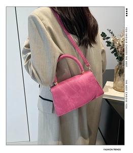 Borsa a tracolla rosa opaca con dettagli dorati su un outfit con blazer a righe