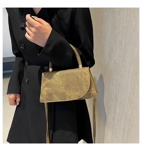 Close-up of vintage bronze square bag with unique gold metallic clasp on black blazer
