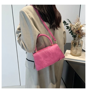 Dettaglio borsa a tracolla rosso rosa con texture opaca e fibbie d'oro su modella