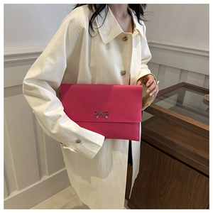 Detail of fuchsia leather envelope bag with a decorative silver metal bow clasp