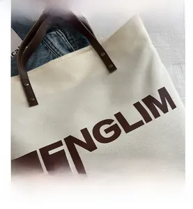 Close-up of canvas tote bag with brown leather handles and rivet details
