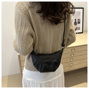 Model view of black croissant bag with pleated texture and adjustable knot shoulder strap