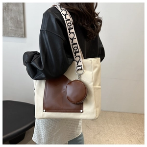 Detail of canvas tote bag with brown leather pocket and patterned woven strap