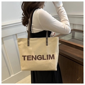 Detail view of large canvas tote bag with brown leather straps and TENGLIM print