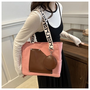 Detail of pink canvas tote bag featuring brown leather pocket and contrast logo straps