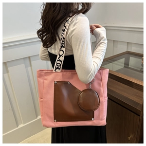 Detail of pink canvas tote with brown leather pocket and black and white patterned strap