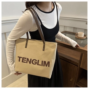 Detail of canvas tote bag with TENGLIM logo and brown leather straps on a model