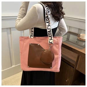 Detail of pink canvas tote with brown leather pocket and patterned wide strap shoulder view