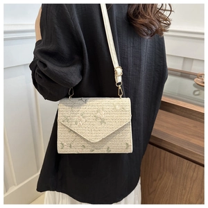 Détail d'un sac bandoulière en paille tressée avec broderie florale et lanière