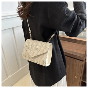 Detail of cream straw crossbody bag with floral embroidery and white leather trim