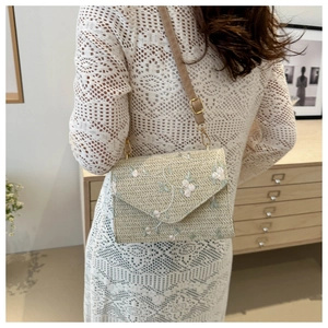 Détail d'un sac bandoulière tissé beige avec broderies florales et fine bandoulière marron
