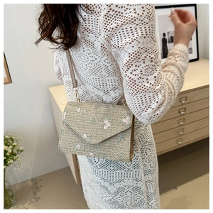 Détail du sac bandoulière en paille tressée avec broderies florales et fine bandoulière