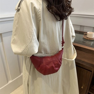 Minimalist deep red leather croissant bag with pleated design and matching shoulder strap