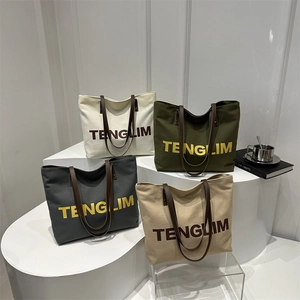 Large canvas tote bags with leather handles in multiple colors and bold text print