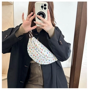 Mirror selfie showing the fit and scale of the white polka dot canvas crossbody bag