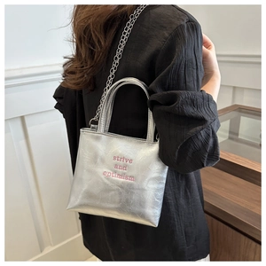 Dettaglio della borsa tote argento metallizzato con ricamo rosa strive and optimism