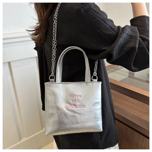 Dettaglio della borsa tote argento con ricamo rosa e tracolla a catena alla moda
