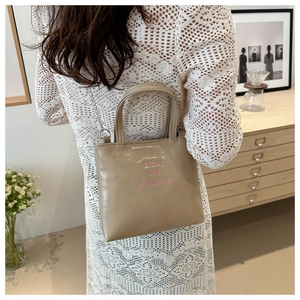 Dettaglio borsa tote kaki con ricamo rosa e tracolla a catena d'argento di alta qualità