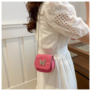 Detail of a pink mini crossbody bag with a silver butterfly buckle and chain strap