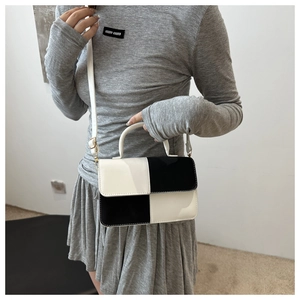 Dettaglio di una borsa a tracolla chic bicolore bianca e nera con manico superiore