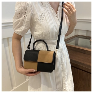 Dettaglio di una mini borsa a tracolla bicolore nera e marrone con finiture dorate