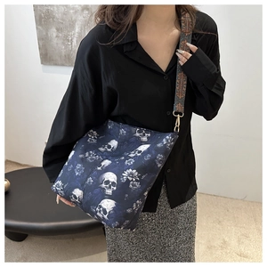 Detail of canvas crossbody bag showing skull and floral print with ethnic woven strap
