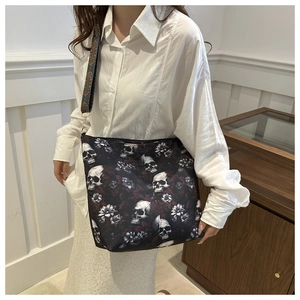 Detail of gothic skull and floral print tote bag with wide textured woven strap