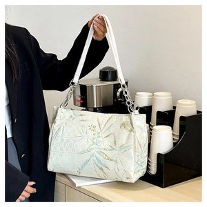 Nahaufnahme der Schultertasche mit Blattmuster und silberner Metallkette mit weißem Leder