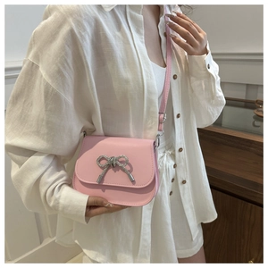 Close-up of pink saddle bag featuring a sparkling rhinestone bow buckle detail
