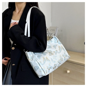 Detail of light blue butterfly print tote bag with white leather strap and silver chain