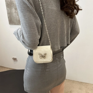 White minimalist crossbody saddle bag with silver butterfly charm and chain strap