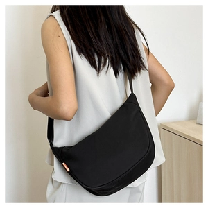 Detail of a black half-moon crossbody bag with adjustable strap and orange side label