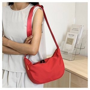 Detail of red crescent nylon shoulder bag with adjustable strap and orange side label