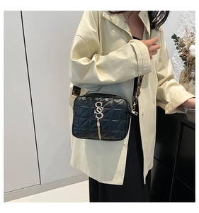 Detail of black quilted camera bag with gold S logo and contrast patterned wide strap