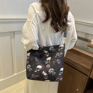 Black leather shoulder bag with skull rose print and geometric woven strap on a model